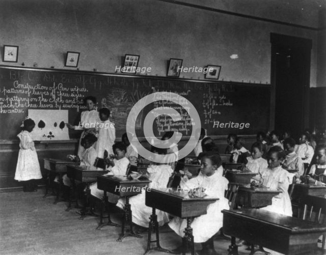 African American schoolgirls in classroom, learning to sew, (1899?). Creator: Frances Benjamin Johnston.