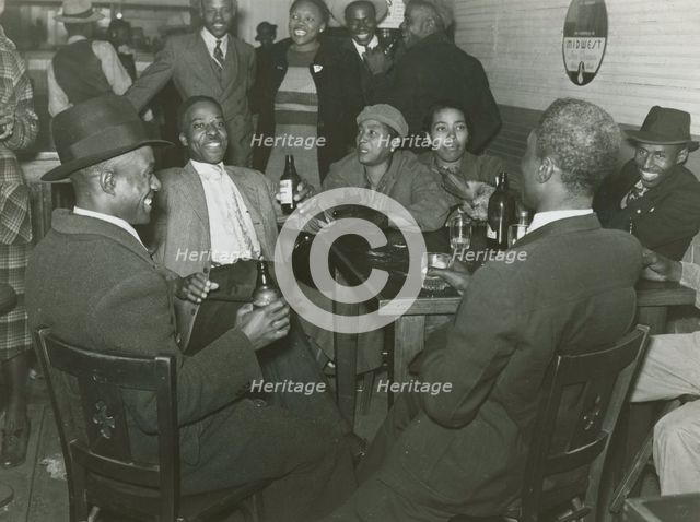 African Americans conversing and drinking beers in a bar, Clarksdale, Mississippi Delta, Nov 1939. Creators: Farm Security Administration, Marion Post Wolcott.