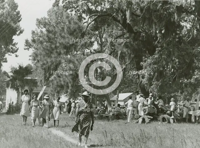 African Americans walking in an open field at a picnic, Beaufort, South Carolina, July 4, 1939. Creators: Farm Security Administration, Marion Post Wolcott.