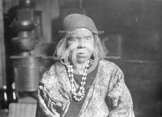 Ainu woman wearing a headscarf, earrings, and a necklace, 1908. Creator: Arnold Genthe.
