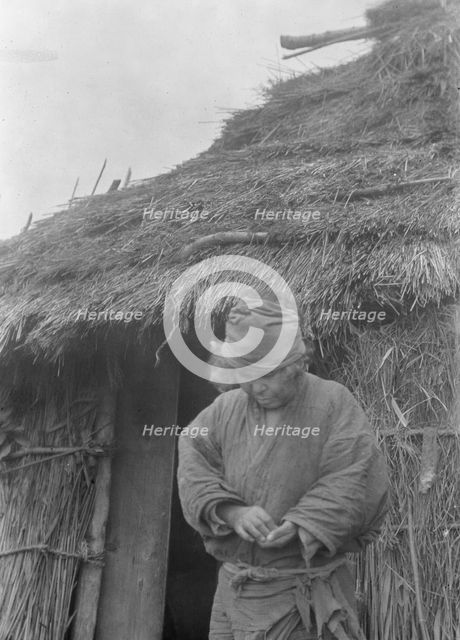 Ainu woman outside a hut, 1908. Creator: Arnold Genthe.
