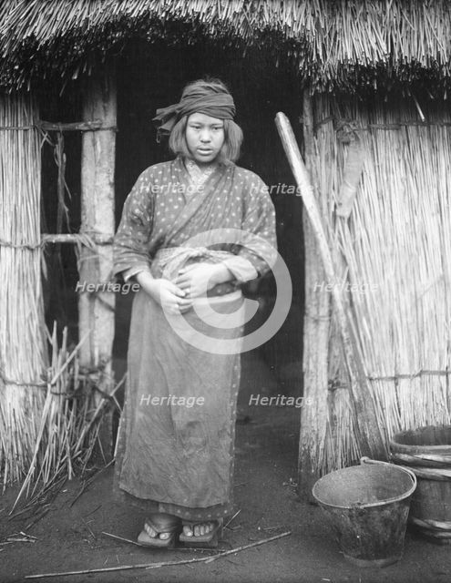 Ainu woman standing by the doorway of a hut, 1908. Creator: Arnold Genthe.
