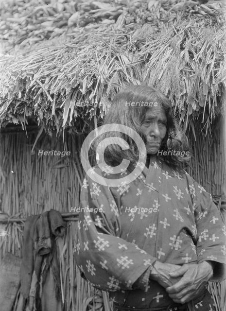 Ainu woman standing outside a hut, 1908. Creator: Arnold Genthe.