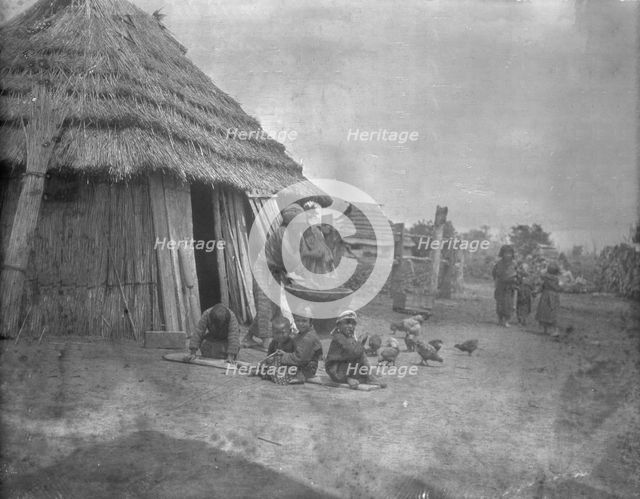 Ainu women and children outside a hut, 1908. Creator: Arnold Genthe.
