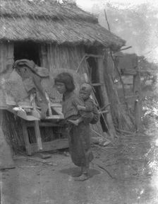 Ainu child carrying a baby on back, 1908. Creator: Arnold Genthe