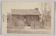 Albumen print of a woman and two children in front of a log house in Georgia, 1880s. Creator: H. S. Clark