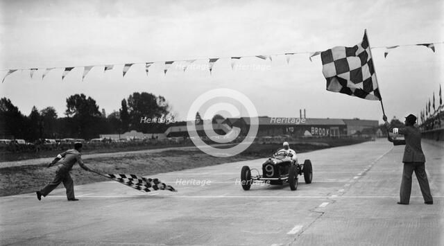 Alfa Romeo taking the chequred flag in a race at Brooklands. Artist: Bill Brunell.