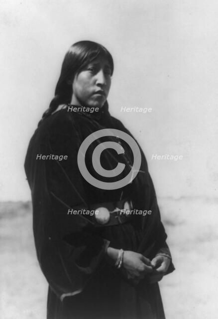 Arapaho maiden, three-quarter-length portrait, standing, facing right, c1910. Creator: Edward Sheriff Curtis.
