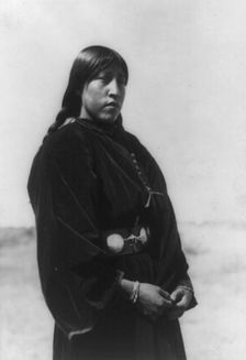Arapaho maiden, three-quarter-length portrait, standing, facing right, c1910. Creator: Edward Sheriff Curtis