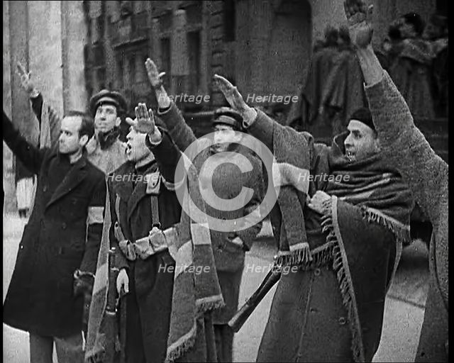 Armed Men and Civilians Making Fascist Salutes in a Street in Madrid, All Dressed in Thick..., 1939. Creator: British Pathe Ltd.