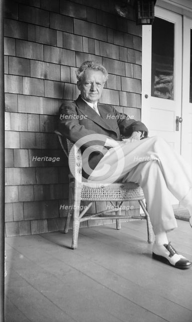 Arnold Genthe seated in a chair on a porch, between 1911 and 1942. Creator: Arnold Genthe.