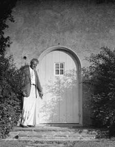 Arnold Genthe standing outside by a door, between 1911 and 1942. Creator: Arnold Genthe
