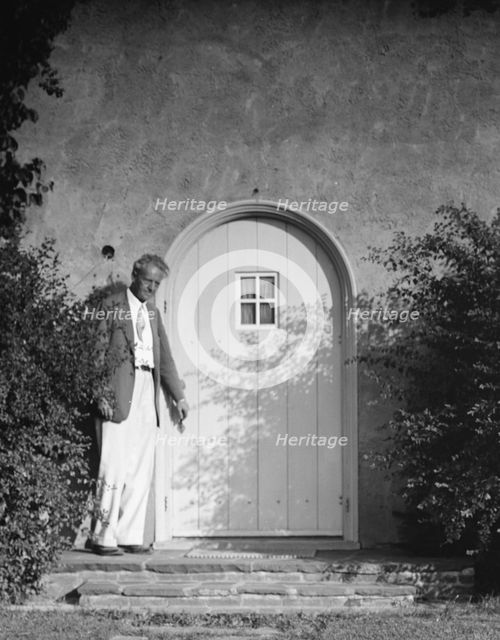 Arnold Genthe standing outside by a door, between 1911 and 1942. Creator: Arnold Genthe.