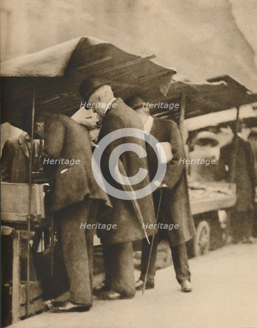 'At One of the Bookstalls of the Farringdon Road Market', c1935. Creator: Walter Benington.