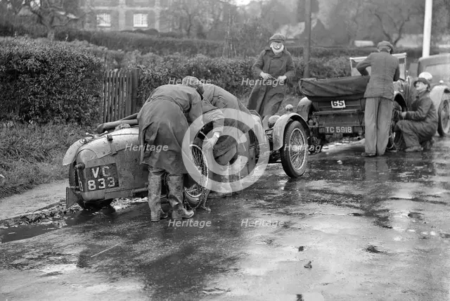 Attaching snow chains to JE Lancaster's Riley Brooklands during the Inter-Varsity Trial, 1930. Artist: Bill Brunell.