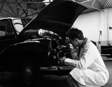 Auto electrician changing a light bulb on a Morris Minor, Nottingham, Nottinghamshire, 1961. Artist: Michael Walters