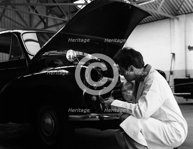Auto electrician changing a light bulb on a Morris Minor, Nottingham, Nottinghamshire, 1961.  Artist: Michael Walters