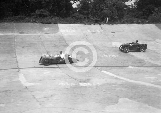 Austin 747 cc with sreamlined racing body leading an MG C type on the Members Banking at Brooklands. Artist: Bill Brunell.
