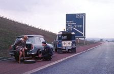 Austin A40 Farina having wheel changed by R.A.C breakdown assistance. Creator: Unknown