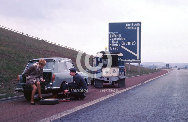 Austin A40 Farina having wheel changed by R.A.C breakdown assistance. Creator: Unknown.