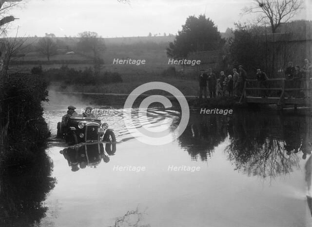 Austin Ulster driving through a ford during a motoring trial, 1936. Artist: Bill Brunell.