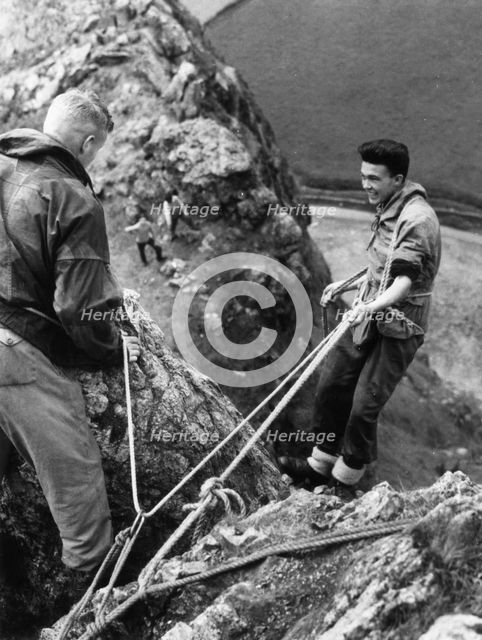 Boy about to start descent of rock face, Outward Bound School, Eskdale, Cumbria,1950. Artist: Unknown