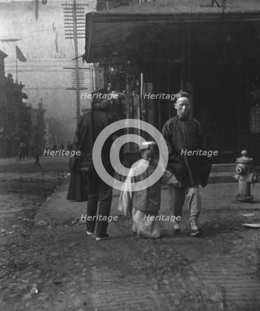 Boy and a man smoking a cigar crossing the street, San Francisco, between 1896 and 1906. Creator: Arnold Genthe.