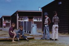 Boy building a model airplane while other children look on, FSA labor camp, Robstown, Tex., 1942. Creator: Arthur Rothstein