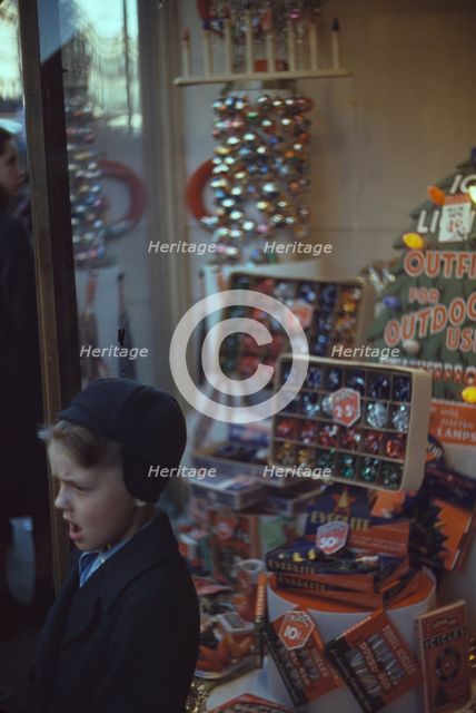 Boy beside store window display of Christmas ornaments, between 1941 and 1942. Creator: Unknown.