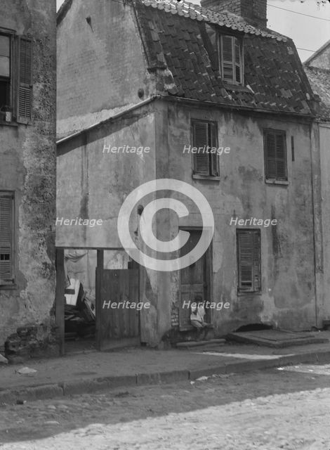 Boy sitting in the doorway of a two-story building, [17 Chalmers Street], Charleston..., c1920-c1926 Creator: Arnold Genthe.