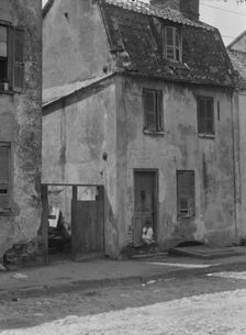 Boy sitting in the doorway of a two-story building, [17 Chalmers Street], Charleston..., c1920-c1926 Creator: Arnold Genthe