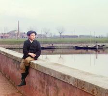 Boy sitting on sea wall, between 1905 and 1915. Creator: Sergey Mikhaylovich Prokudin-Gorsky