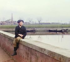 Boy sitting on sea wall, between 1905 and 1915. Creator: Sergey Mikhaylovich Prokudin-Gorsky
