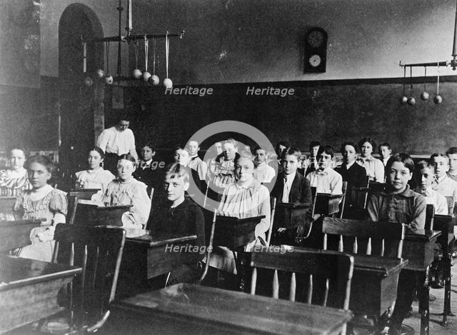 Boys and girls seated at desks in Washington, D.C. classroom, (1899?). Creator: Frances Benjamin Johnston.