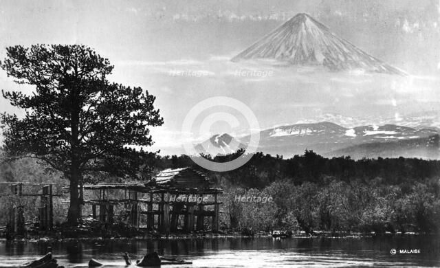 Booths on the river bank against the backdrop of Klyuchevsky volcano, 1922-1923. Creator: Rene Malaise.