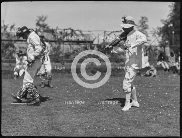 Bampton Morris troupe performing in a 'Pipe Dance', with a fiddle player,  Oxfordshire, 1920-30.  Creator: George R Long.