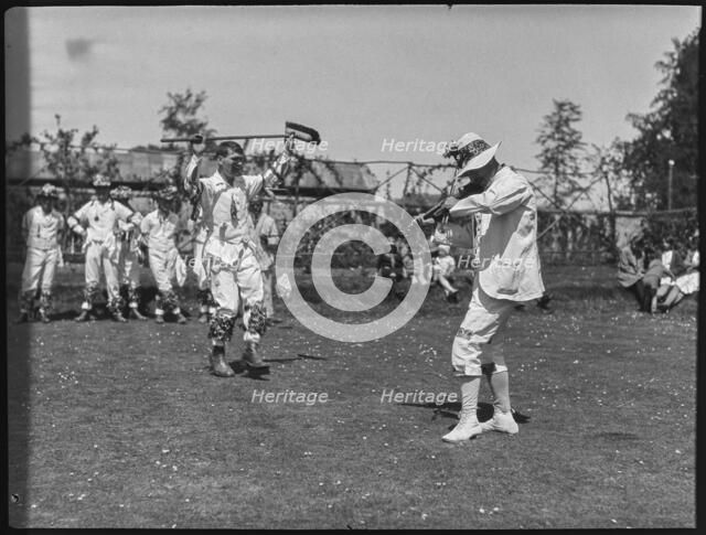 Bampton Morris troupe performing with a fiddler and someone holding a broom aloft, Oxon, 1920-30. Creator: George R Long.