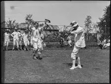 Bampton Morris troupe performing with a fiddler and someone holding a broom aloft, Oxon, 1920-30. Creator: George R Long