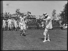 Bampton Morris troupe performing with a fiddler and someone holding a broom aloft, Oxon, 1920-30. Creator: George R Long