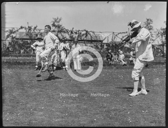 Bampton Morris troupe performing with a fiddler and someone holding a broom aloft, Oxon, 1920-30. Creator: George R Long.