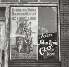 Barber shop window [with circus poster] in Birmingham, Alabama, 1937-01 - 1937-02. Creator: Arthur Rothstein