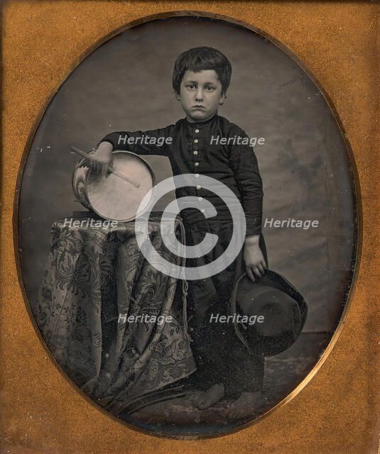 Barefoot Boy Holding Hat and Drum Stick, Leaning Forearm on Child-sized Drum on Table, 1850s. Creator: Unknown.