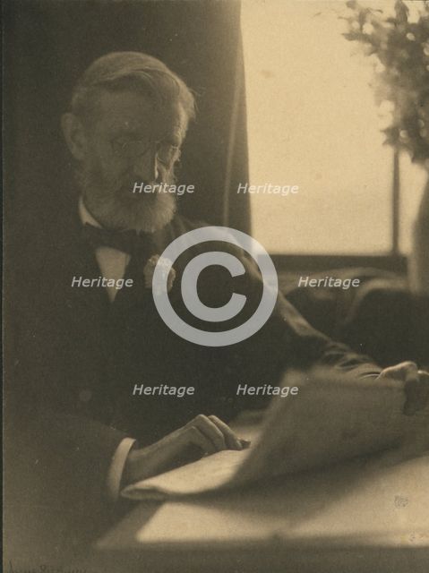Bearded man in spectacles reading a newspaper, c1900. Creator: Anne K Pilsbury.