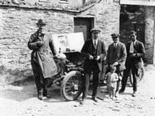 Bedford standing at the front of a car, with onlookers
