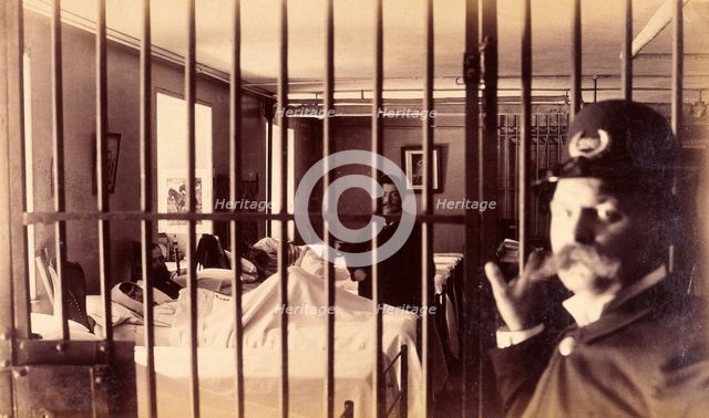 Bellevue Hospital, New York City: male patients (criminal insane?) in bed in ward, prison bars in... Creator: Unknown.