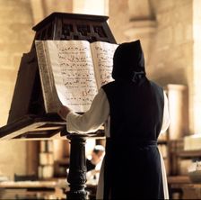 Benedictine monk consulting a song book from the Monastery of Poblet library