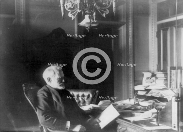 Benjamin Franklin Tracy, Secretary of the Navy, half-length portrait..., looking at paper, c1890. Creator: Frances Benjamin Johnston.