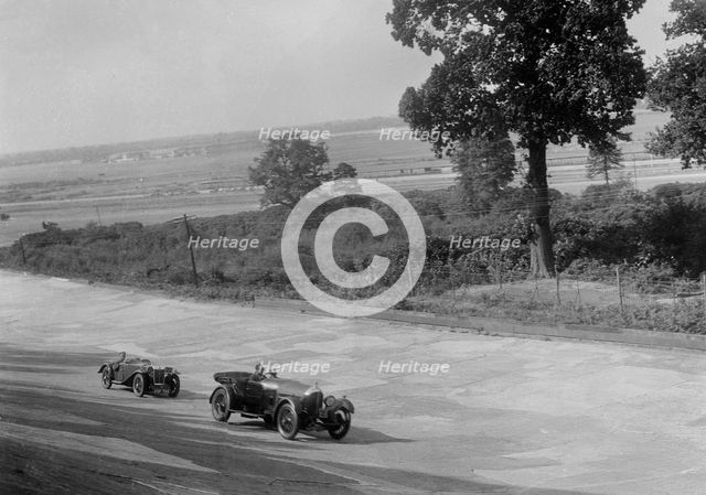 Bentley of FE Elgood and MG Magna of MB Watson racing at a MCC meeting, Brooklands, Surrey, 1933. Artist: Bill Brunell.