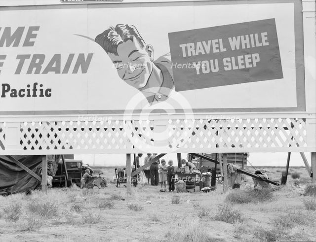 Billboard along U.S. 99 behind which three destitute families..., Kern County, California, 1938. Creator: Dorothea Lange.