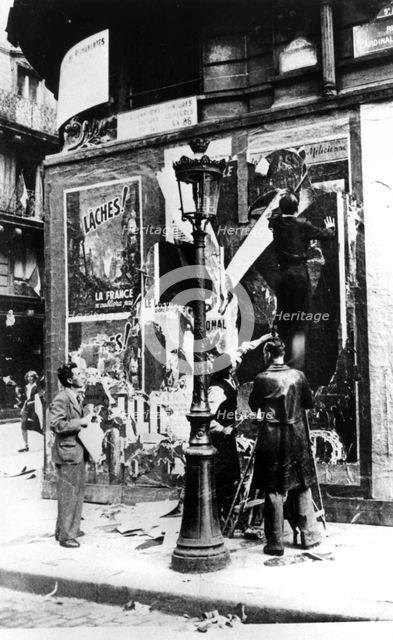 Billboard with men putting up propaganda posters, Paris, World War II, 1939-1945. Artist: Unknown